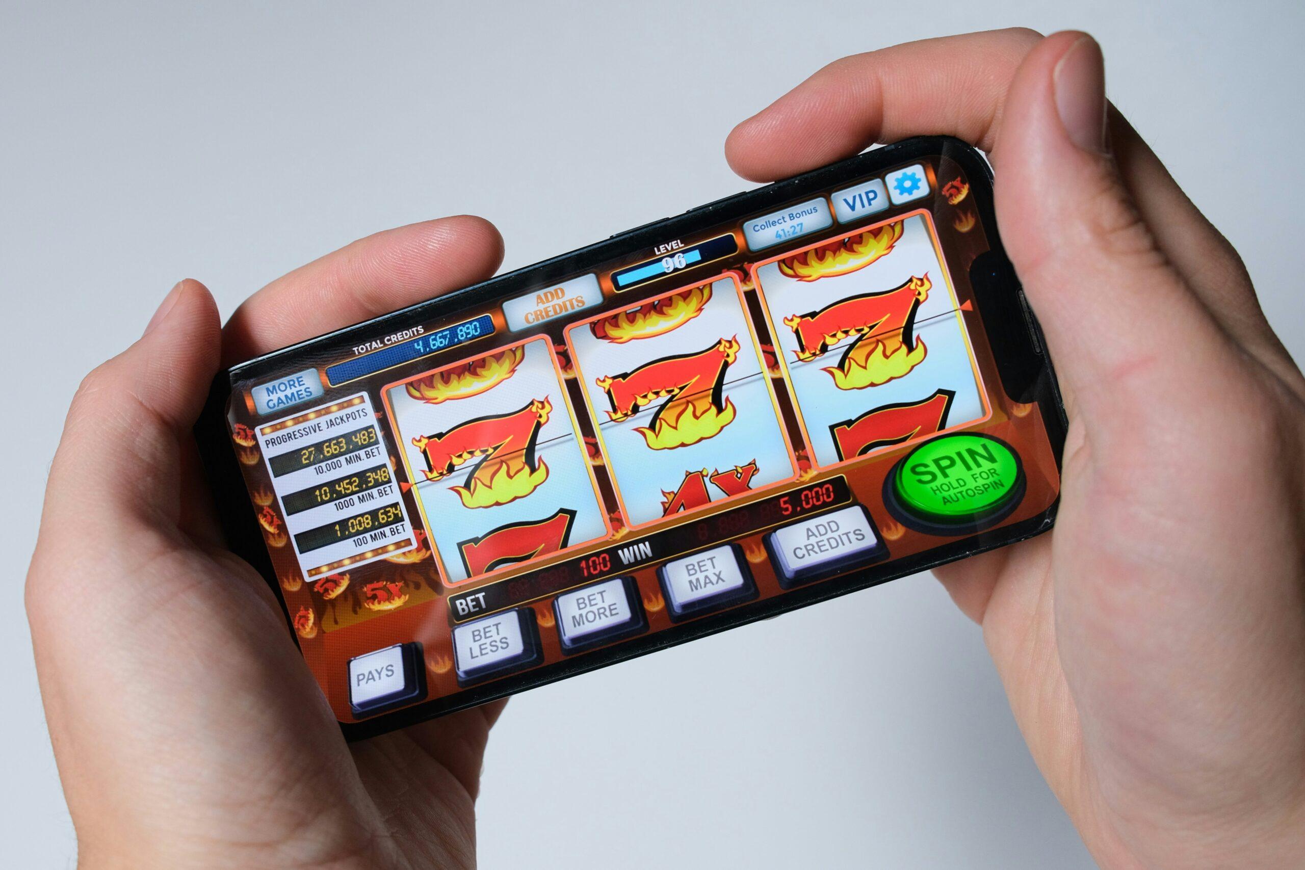 Mano sosteniendo un móvil con un juego de tragaperras, metáfora del refuerzo intermitente